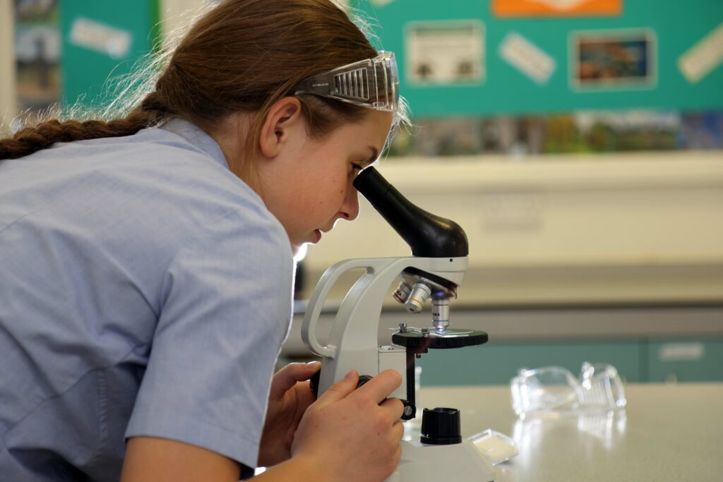 girl looking through microscope